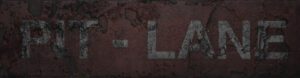 Ein abgenutztes Schild mit der Aufschrift 'PIT-LANE' auf einer rauen Oberfläche.
