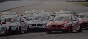 Aufgereihte DTM-Fahrzeuge beim Rennen in Assen 2021: rot-silberne Rennwagen mit Sponsorlogos und FK-Performance-Markierungen auf der Startaufstellung.