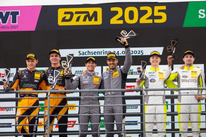 Fünf Rennfahrer stehen auf dem Podium der DTM 2025 mit Pokalen in der Hand.