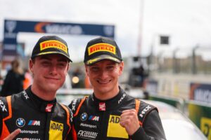 Zwei junge Rennfahrer in Pirelli-Caps posieren lächelnd nach einem Rennen.