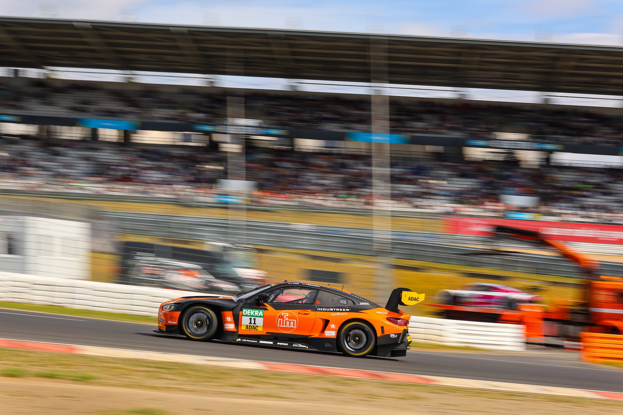 Ein orangefarbener Rennwagen fährt schnell auf einer Rennstrecke während eines Rennens.