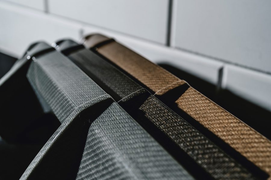 Nahaufnahme von mehreren Naturfaser-Panels mit unterschiedlichen Webmustern und Farbtönen, Hintergrund mit weißen Fliesen.