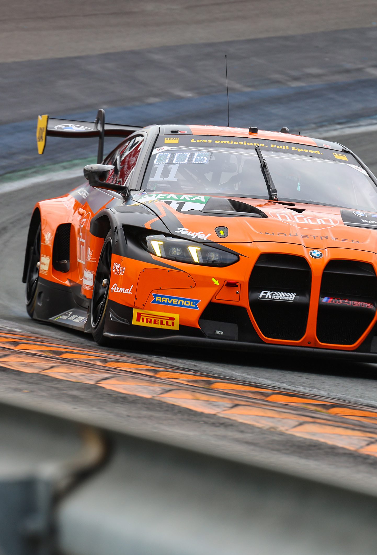 BMW M4 GT3 Nr. 11 in orange und schwarz beim Kurveneintritt auf der Rennstrecke, Sponsorlogos sichtbar.