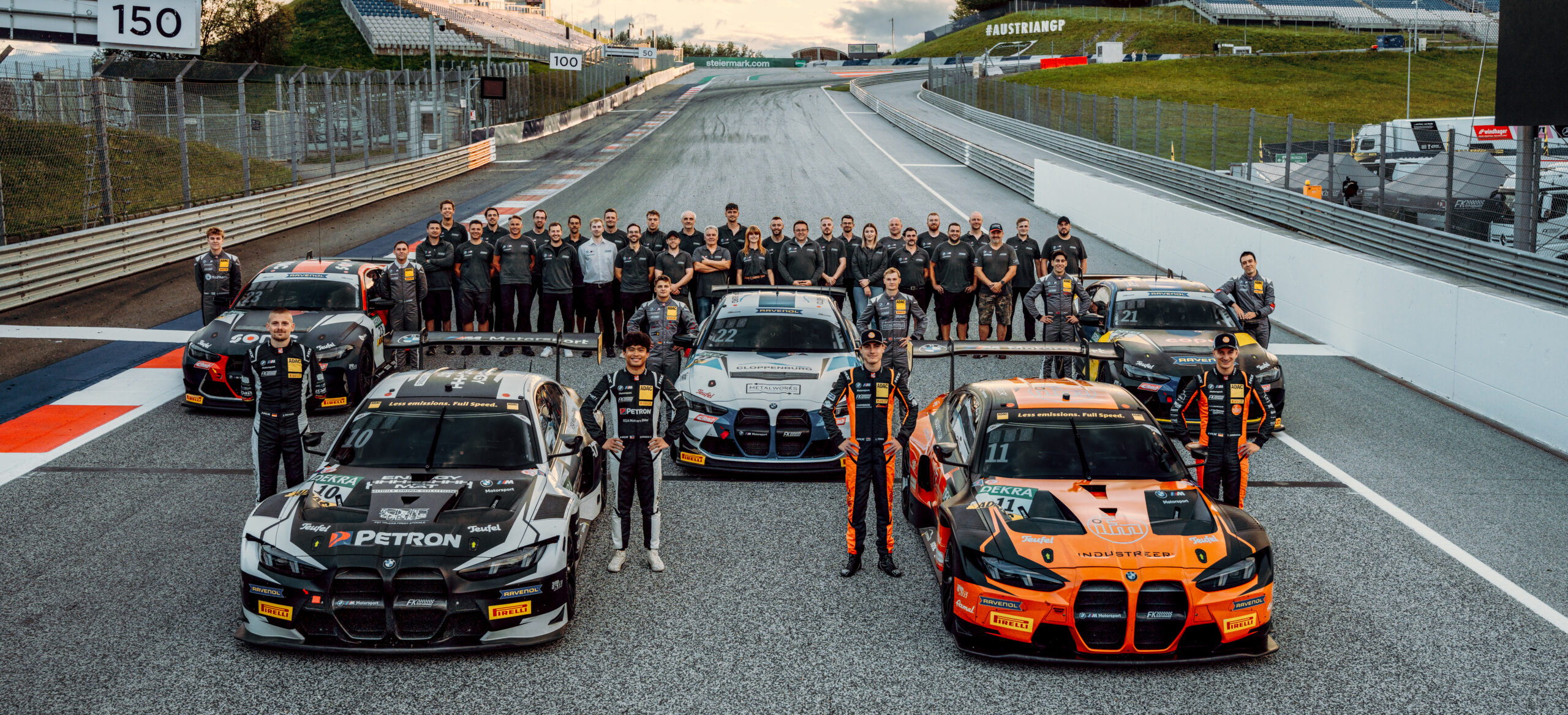 FK Performance Motorsport Team mit Rennfahrern und BMW-Rennwagen auf der Rennstrecke