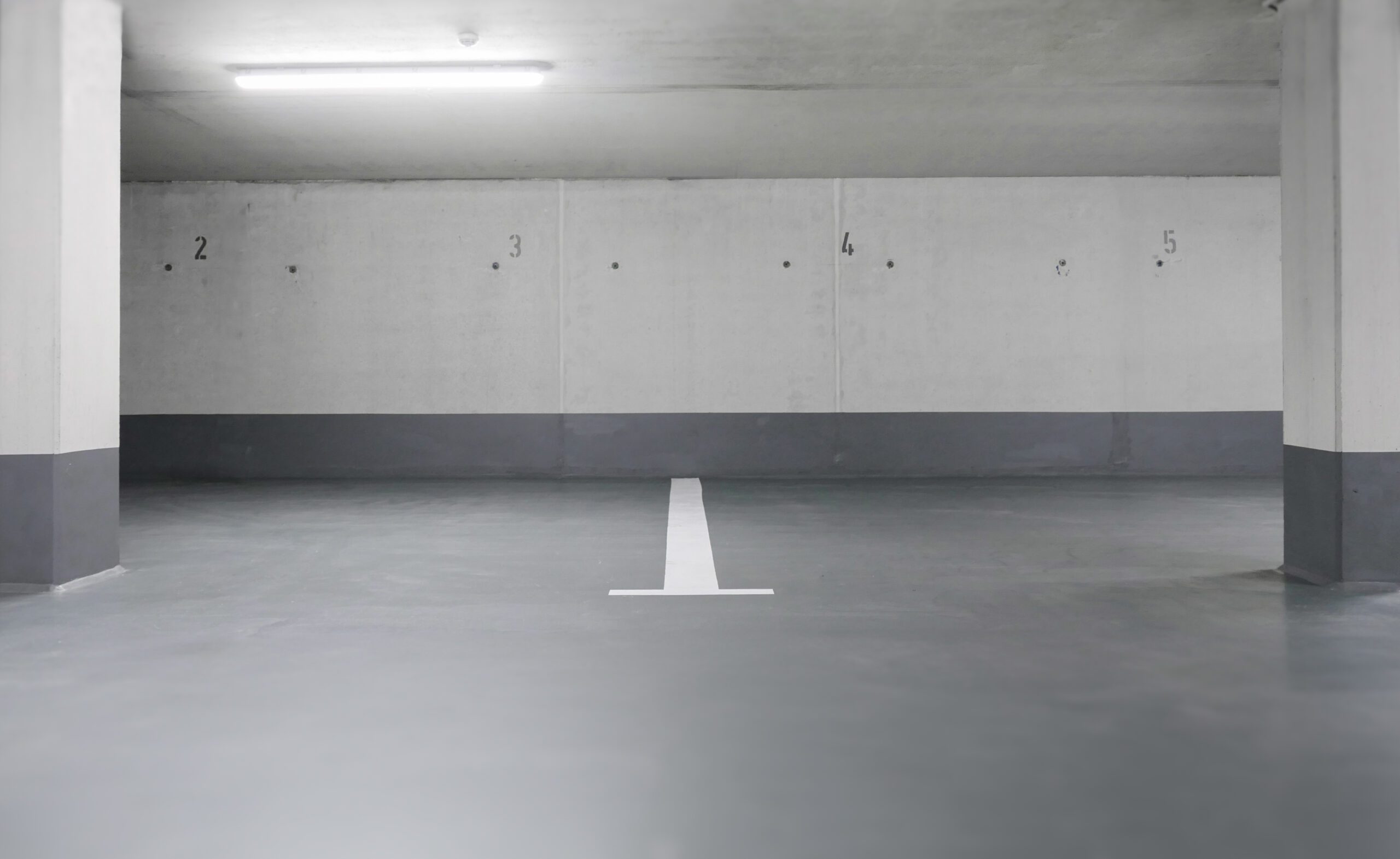 Leere Parkfläche in sauberer Tiefgarage mit nummerierten Stellplätzen 1 bis 5