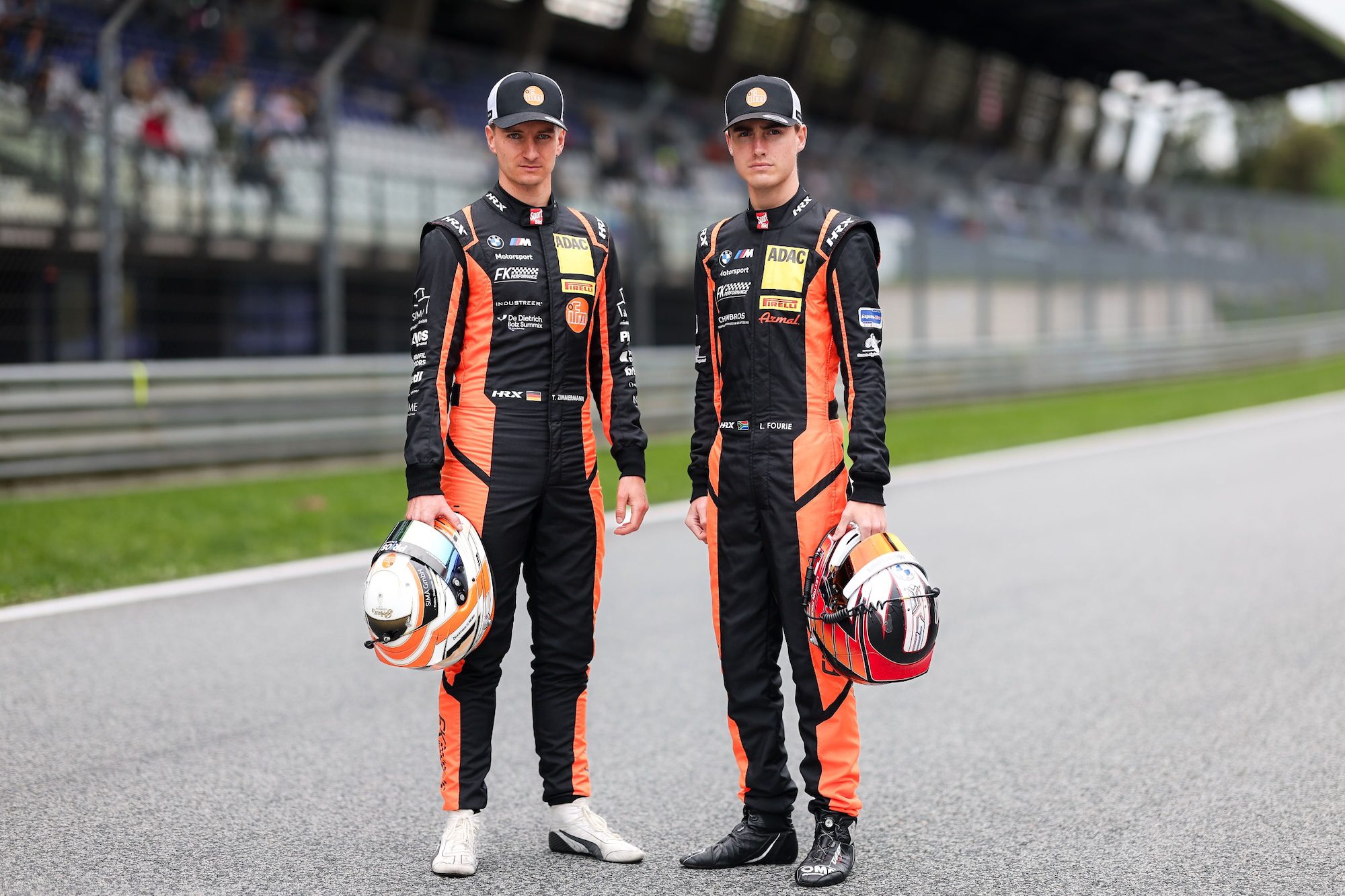 Tim Zimmermann und Leyton Fourie, das Fahrerduo von FK Performance Motorsport für das ADAC GT Masters 2026, posieren in Rennanzügen.
