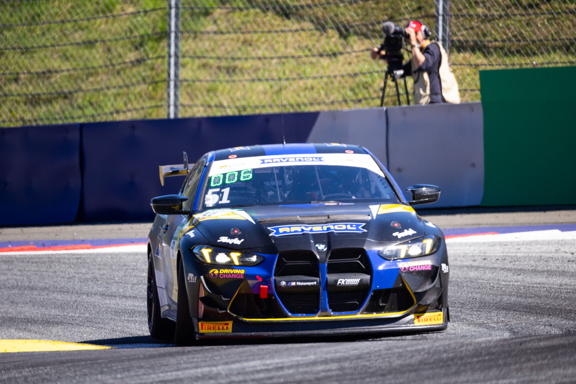 Frontansicht des BMW M4 GT4 von FK Performance Motorsport mit Ravenol-Branding beim Anbremsen einer Kurve.