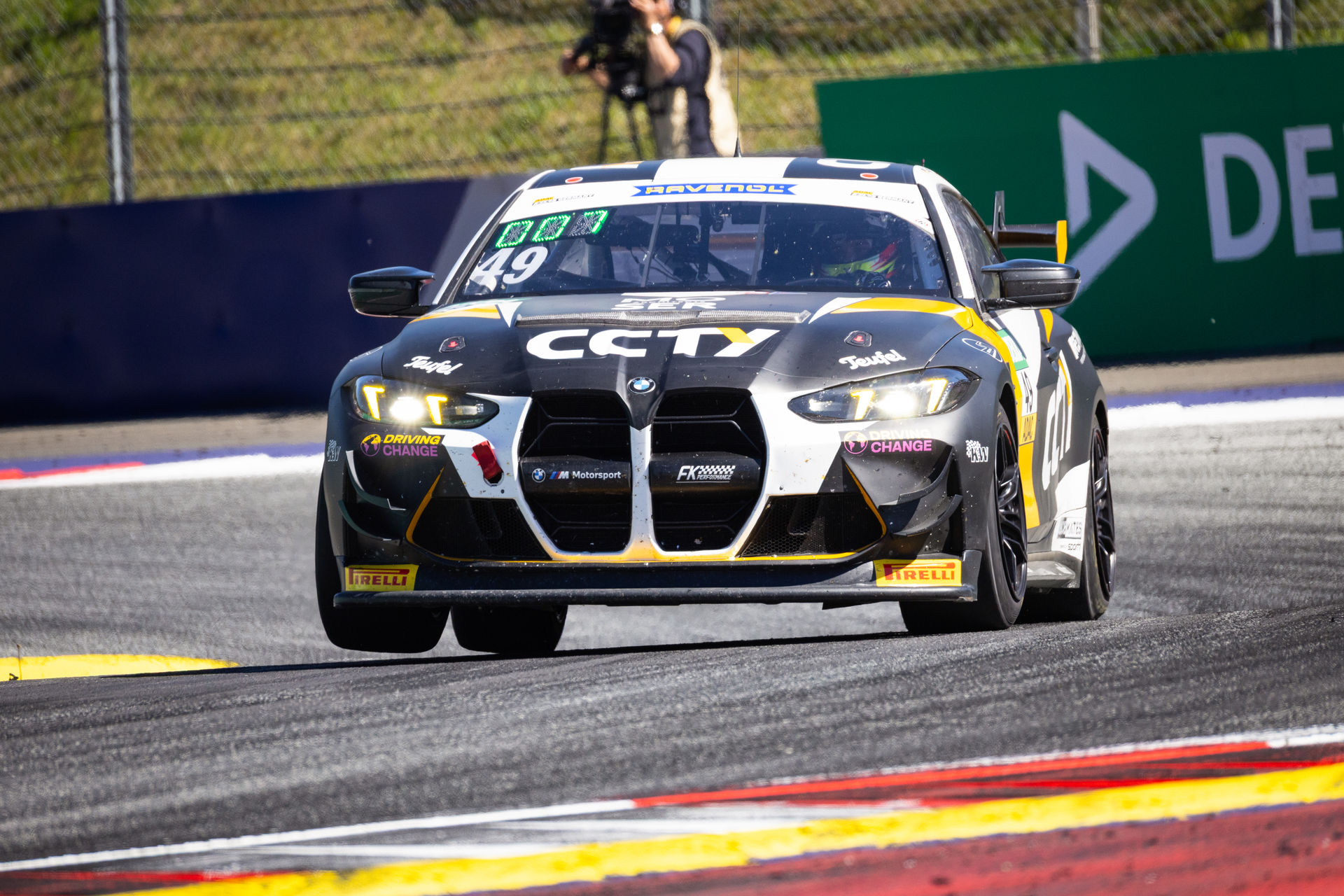 Frontalansicht des BMW M4 GT4 (Startnummer 49) mit CCTY-Sponsoring auf der Rennstrecke beim Überfahren der Curbs.