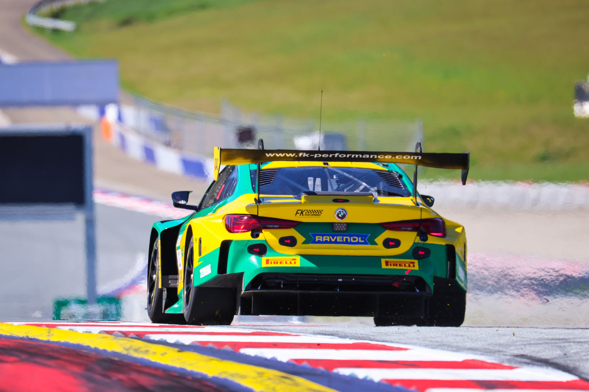 Heckansicht eines BMW M4 GT3 Rennwagens mit großem Heckflügel auf der Zielgeraden.