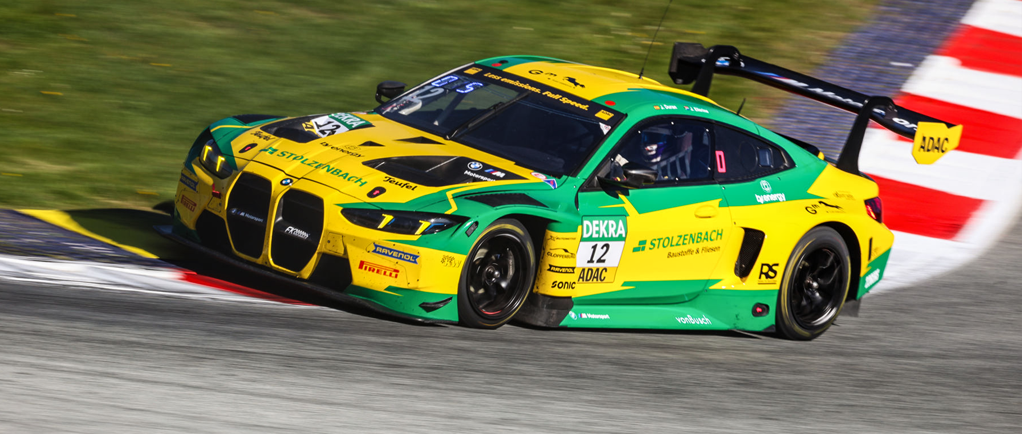 Gelb-grüner BMW M4 GT3 Rennwagen von FK Performance auf der Rennstrecke in einer Kurve.