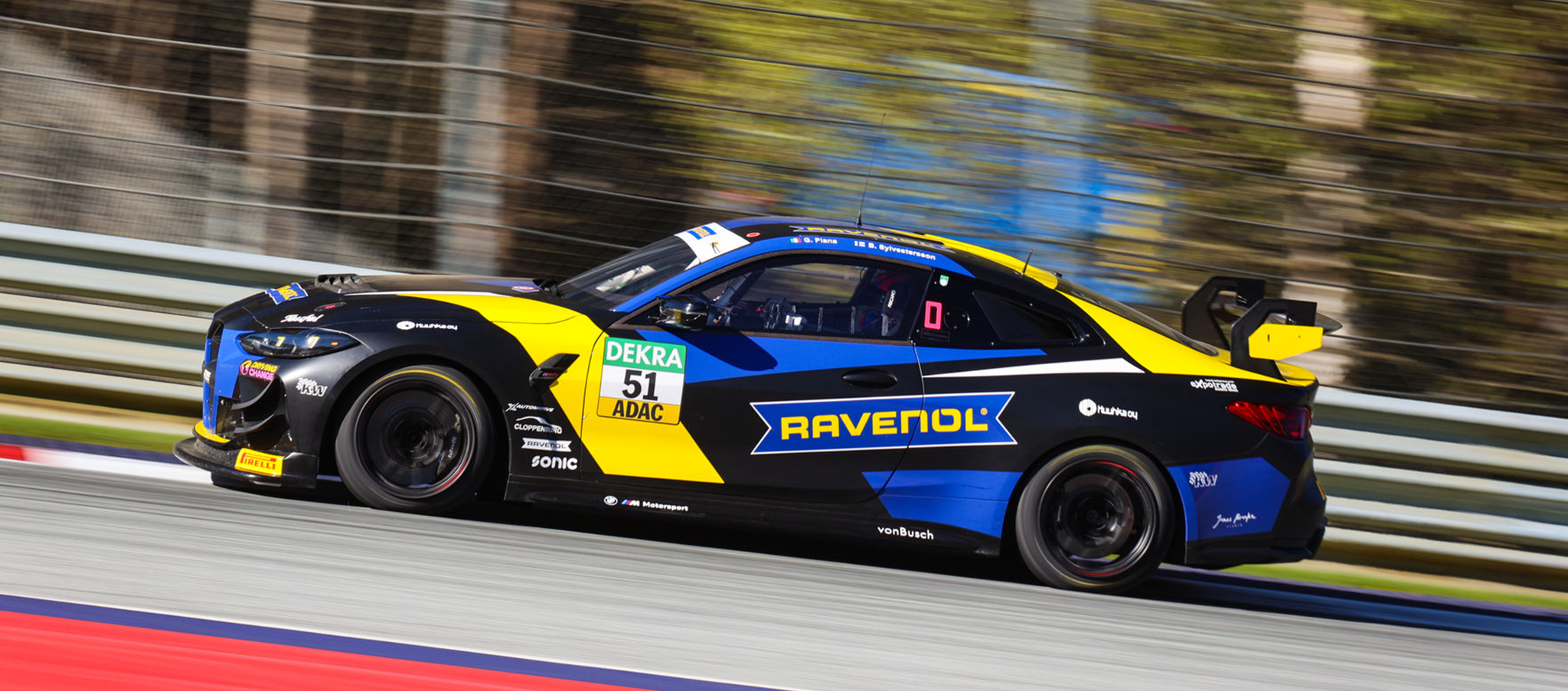Dynamische Seitenansicht des schwarz-blau-gelben BMW M4 GT4 von FK Performance (Startnummer 51) mit Ravenol-Sponsoring auf der Rennstrecke.