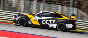 Seitliche Profilansicht des BMW M4 GT4 im CCTY-Design während einer schnellen Fahrt auf der Rennstrecke.
